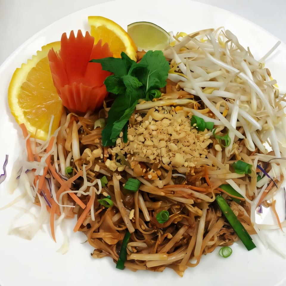 Thai Aroy Dee's Pad Thai with noodles, bean sprouts, peanuts, lime, orange, and carved carrot garnish.